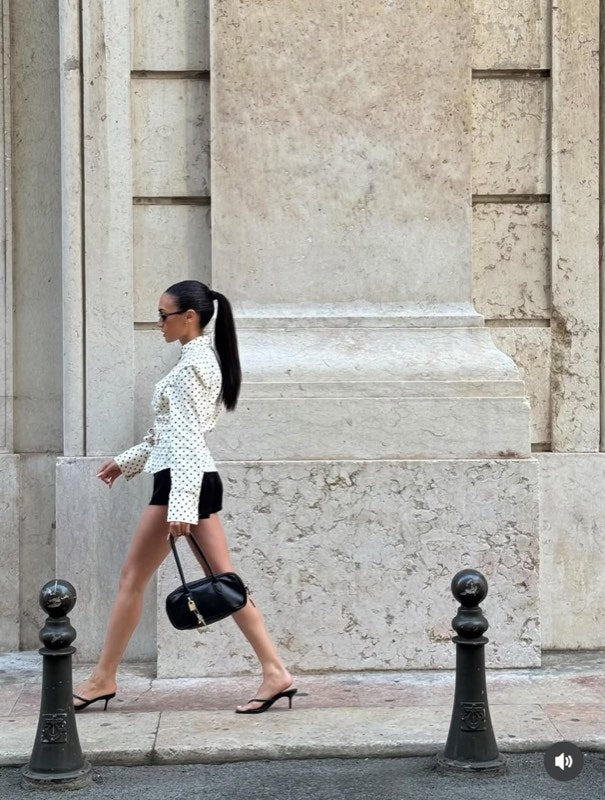 White polka dot shirt styled with black shorts and a handbag